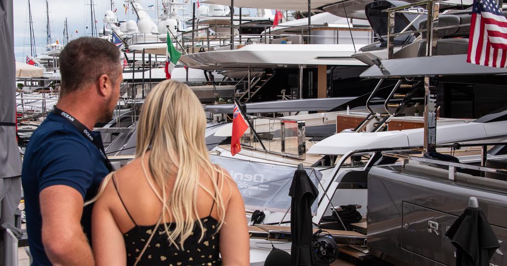 A couple of people looking out over a lineup of superyachts at the Monaco Yacht Show
