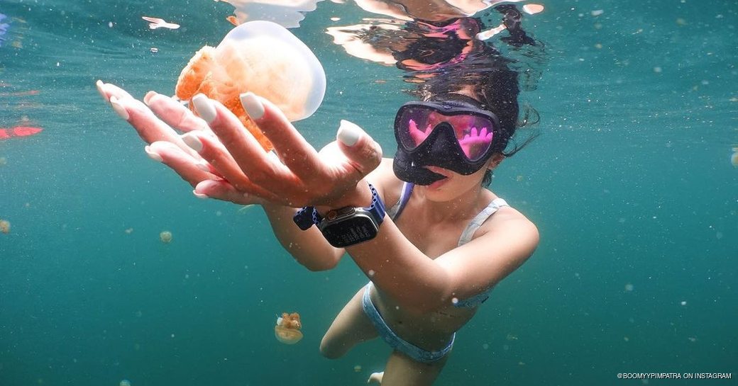 Girl in snorkeling gear holding jellyfish 
