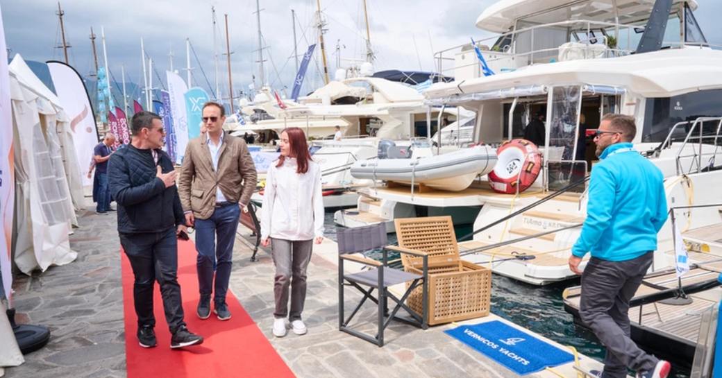 Visitors to the East Med Multihull & Yacht Charter Show standing on red carpet next to berthed yacht charters