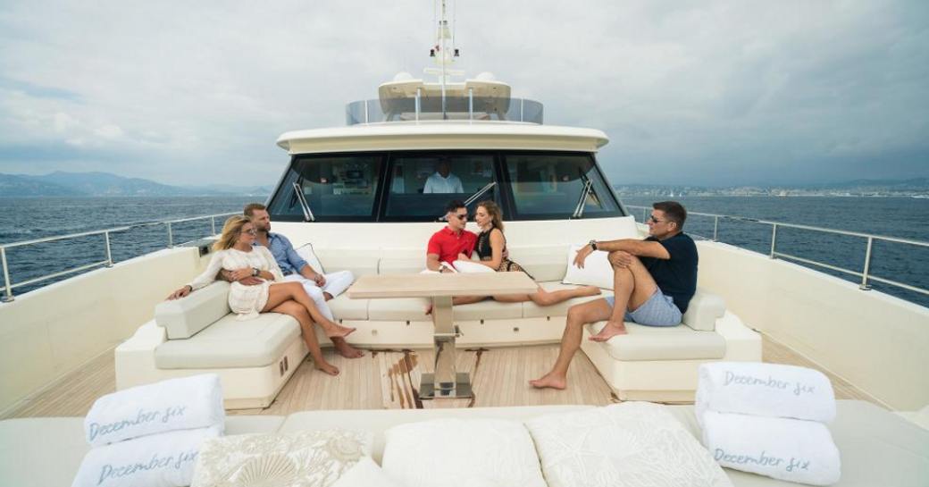 charter guests relax in the seating area on the foredeck of motor yacht December Six 