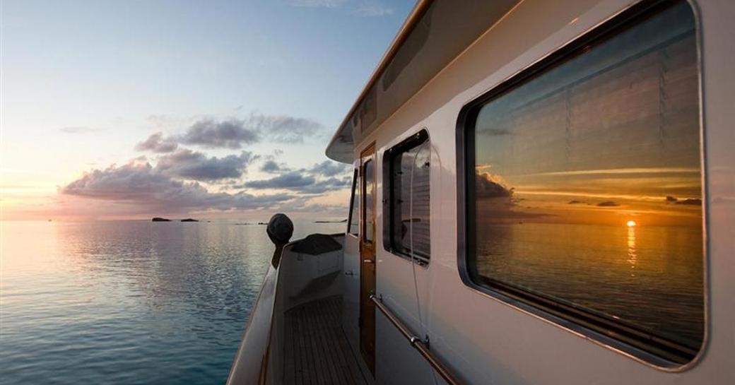 the side deck of superyacht BERILDA reflects the beautiful Caribbean sunset