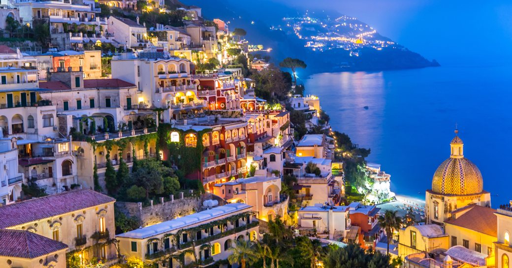 italian town of positano by night, glittering buildings and shining sea
