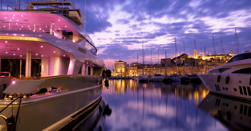 Superyachts moored in Cannes' Vieux Port in a purpling twilight