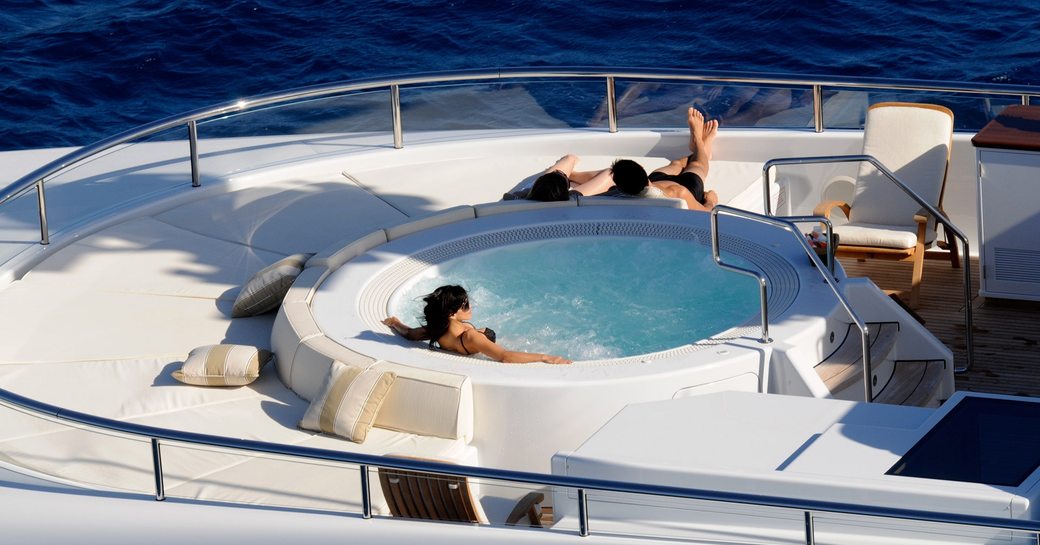 Charter guests relax in the sun deck jacuzzi on board motor yacht Harle