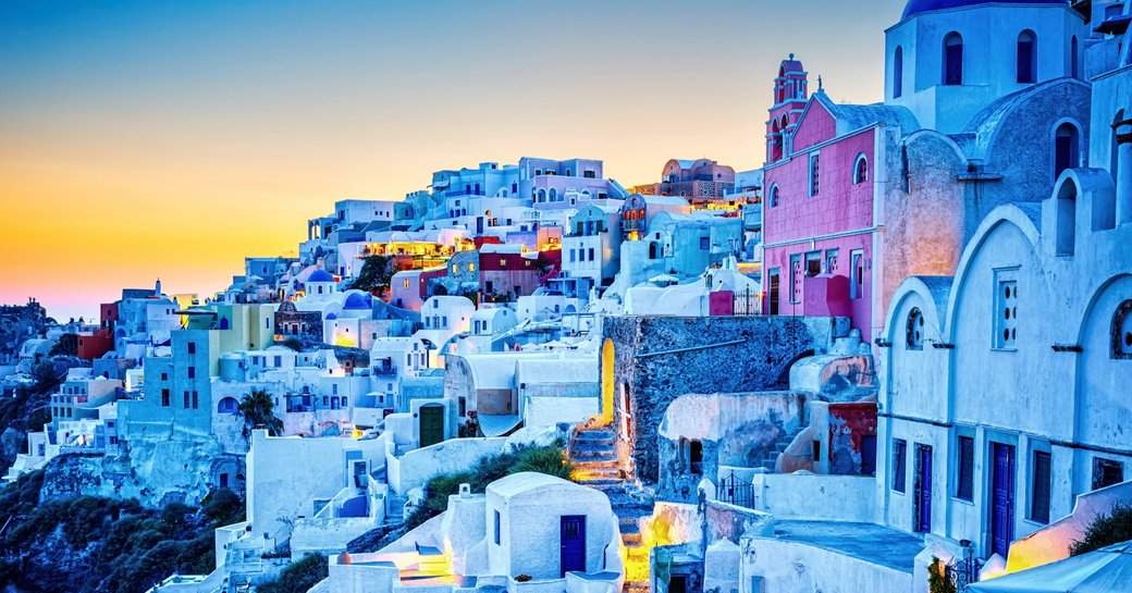white-washed architecture of Oia hillside as sun sets in Santorini, Greece