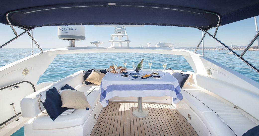 Overview of the flybridge onboard Private yacht charter MEDITERRANI IV, white seating around the edges with a square dining table in the center