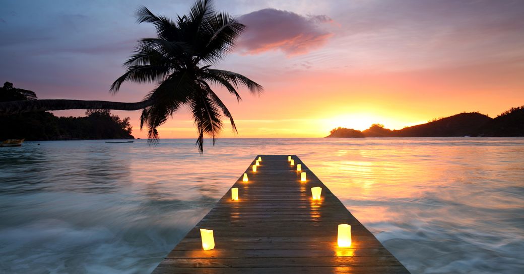 Wooden jetty over a beach at sunset with candles, in romantic Seychelles island in the Indian Ocean