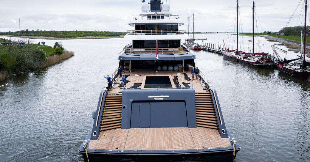 Aft view of Feadship Project 1012 in transit along river
