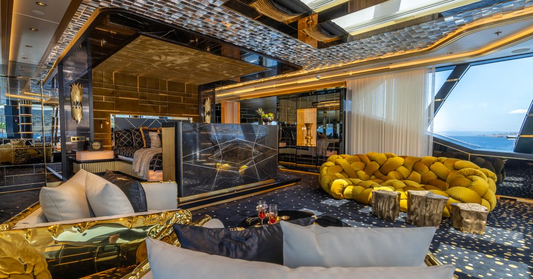 Overview of the master cabin onboard superyacht LEONA, featuring black and gold tones with wide window.
