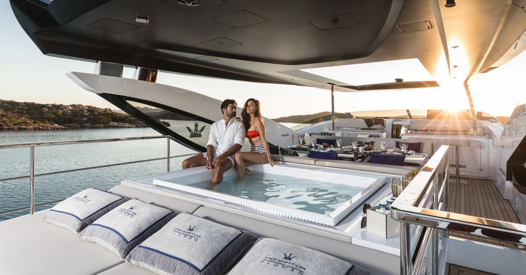 man and woman sit on the edge of spa pool on board luxury yacht hanaa