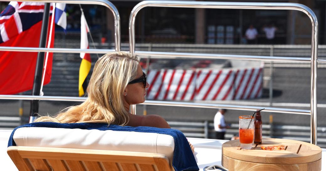 A charter guest soaking up the sun trackside on board a superyacht at the Monaco Grand Prix