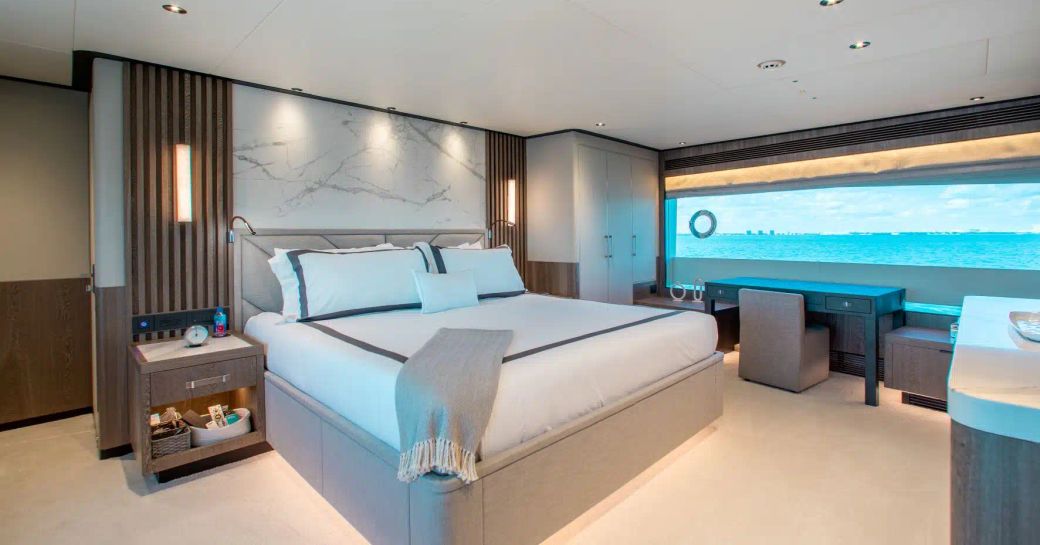 Master cabin onboard charter yacht FREEDOM, central berth facing forward with bureau and large stretched window in the background