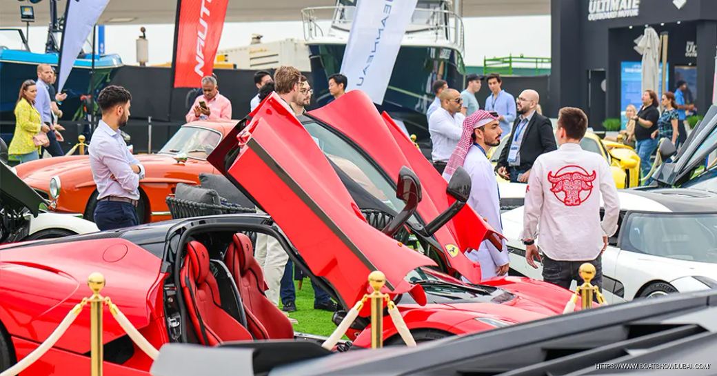Overview of Supercar Avenue at the Dubai International Boat Show, multiple cars with their doors open and visitors walking around