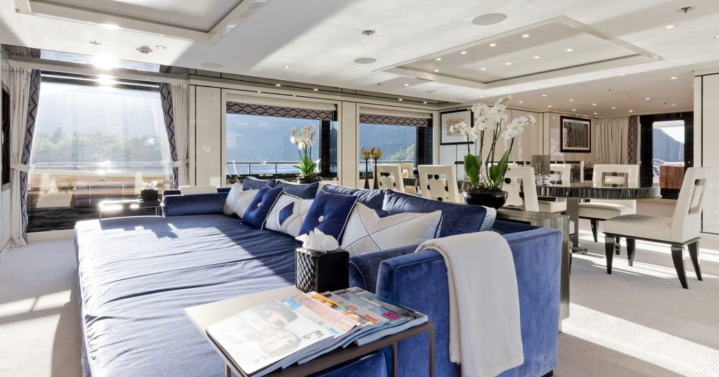 Overview of the main salon onboard charter yacht AMIGOS, lounge on the foreground with a dining area in the background