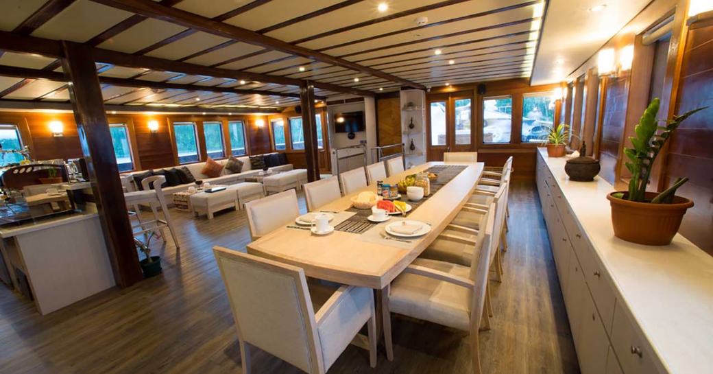 14-seater dining table adjoins a lounge area in the main salon of superyacht LAMIMA 