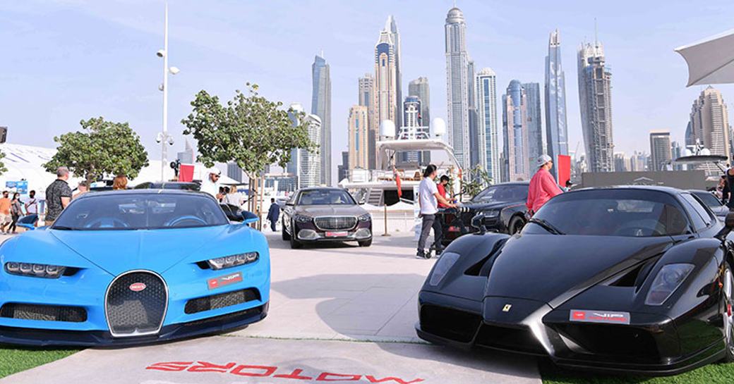 Supercars on display at Dubai Harbour, with skyline visible in background.