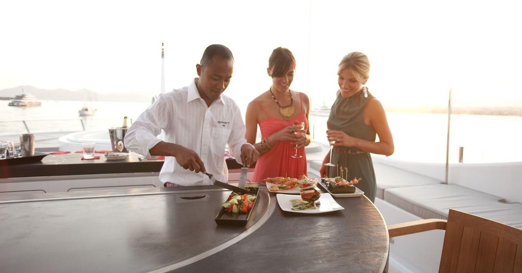 a chef prepares a delicious tepanyaki meal for some guests who are on luxury yacht charter vacation 