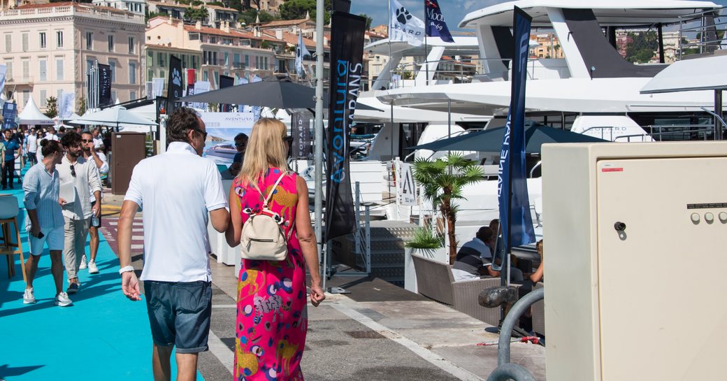 Visitors at the Cannes Yachting Festival walking along and viewing berthed motor yacht charters
