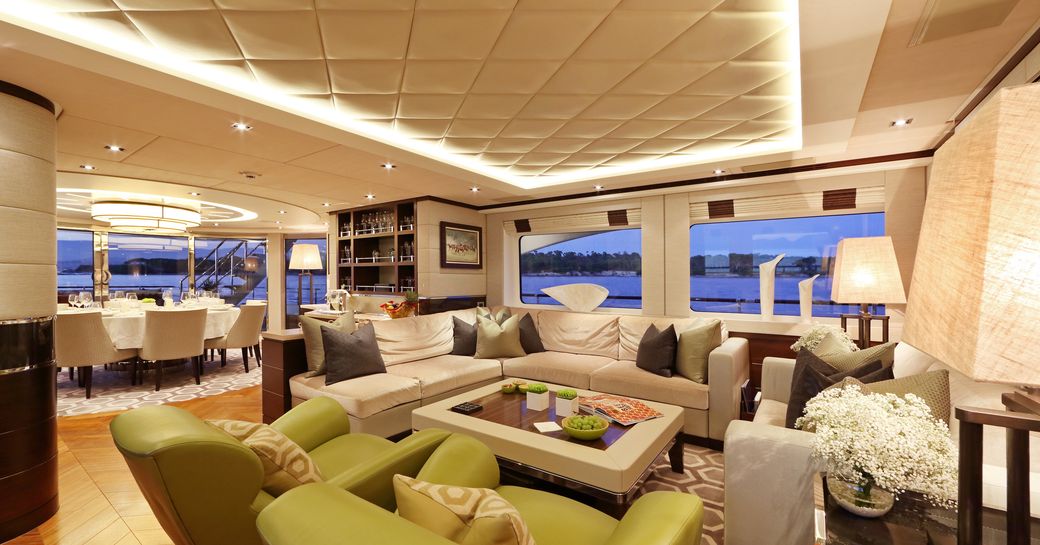 Main salon of luxury yacht AURELIA, with green sofas, white quilted ceilings and discreet lighting panels