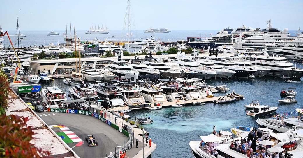 Port Hercule filled with super yacht charters with a Formula One racing car speeding by