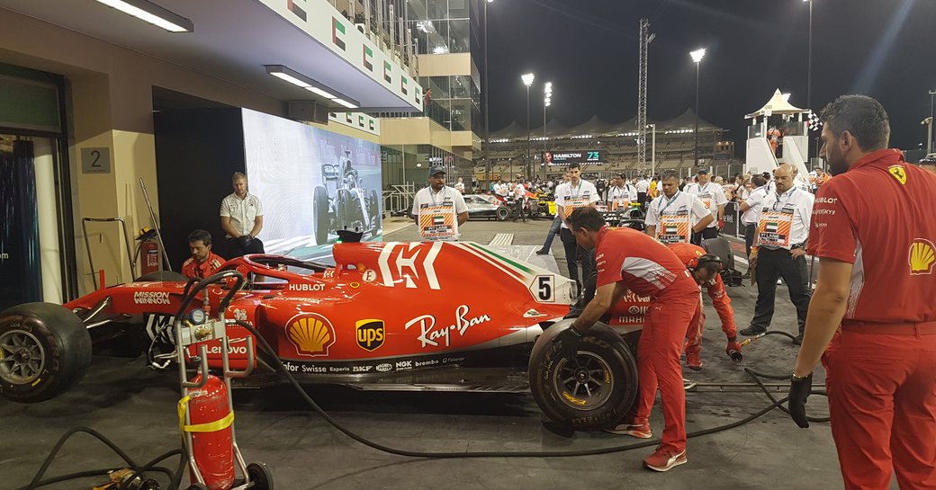 Formula 1 team in the pits at night during the Abu Dhabi Grand Prix, crew surrounding car.