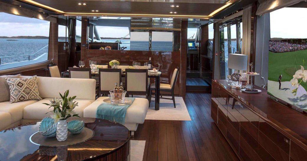 the cosy and welcoming main salon of charter yacht hot pursuit with formal dining area and 55 inch flat screen tv