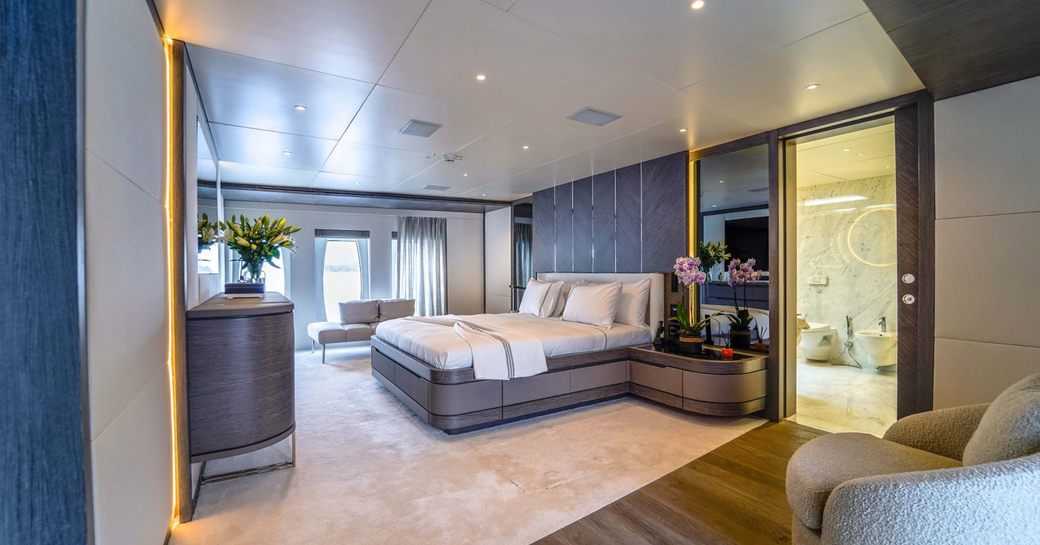 Master cabin onboard charter yacht FORTUNA, central berth facing port with seating area in the foreground and large windows aft 