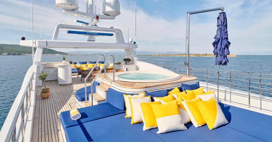 Overview of the sun deck onboard charter yacht TIMBUKTU, central deck Jacuzzi with blue sun pads and yellow cushions