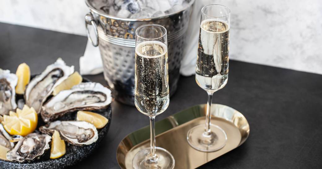 Champagne glasses with sparkling wine and bottle in bucket near oysters