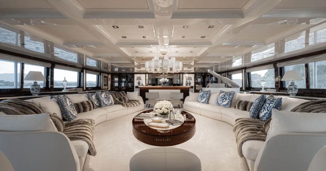 Interior lounge area onboard luxury charter yacht EMIR, abundant plush white seating around the walls with a large coffee table center