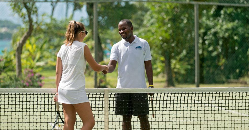 A couple shake hands after a game of tennis in Petit St Vincent, Caribbean