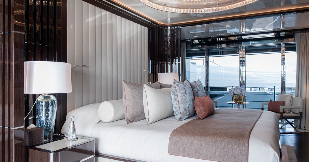 Master cabin onboard charter yacht RESILIENCE, central berth facing starboard with large full-height windows in the background