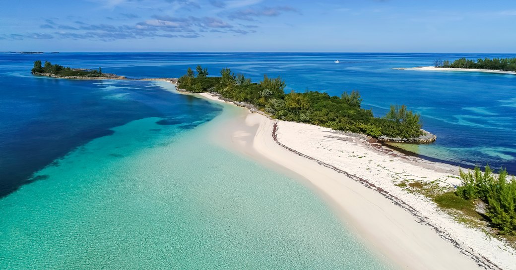 Bahamas blue sea and sand bar lined with vegetation