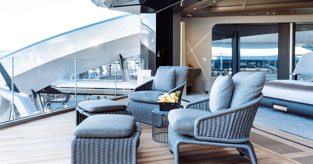 Alfresco seating area onboard charter yacht THIS IS IT, grey wicker armchairs with matching foot stalls