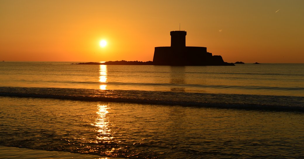 An Autumn sunset with a 19th century military tower from the Napoleonic Wars surrounded by a calm sea.