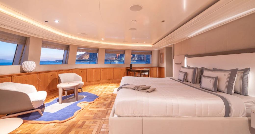 Master cabin onboard Charter yacht CARINTHIA VII, central berth facing forward with two armchairs and windows across the wall. 