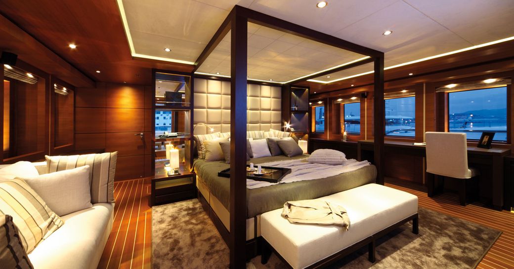 owners cabin on motor yacht zaliv iii with 4 poster bed in centre and wooden accents