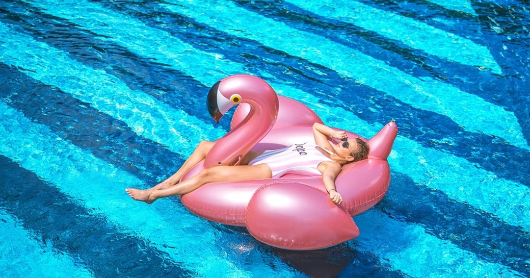 A women lying on an inflatable pink flamingo in a swimming pool in Phuket, Thailand