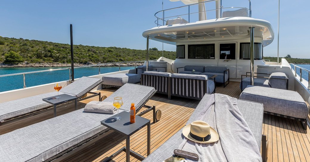Overview of the sun deck onboard charter yacht KLOBUK, sun loungers in the foreground with a lounge area aft