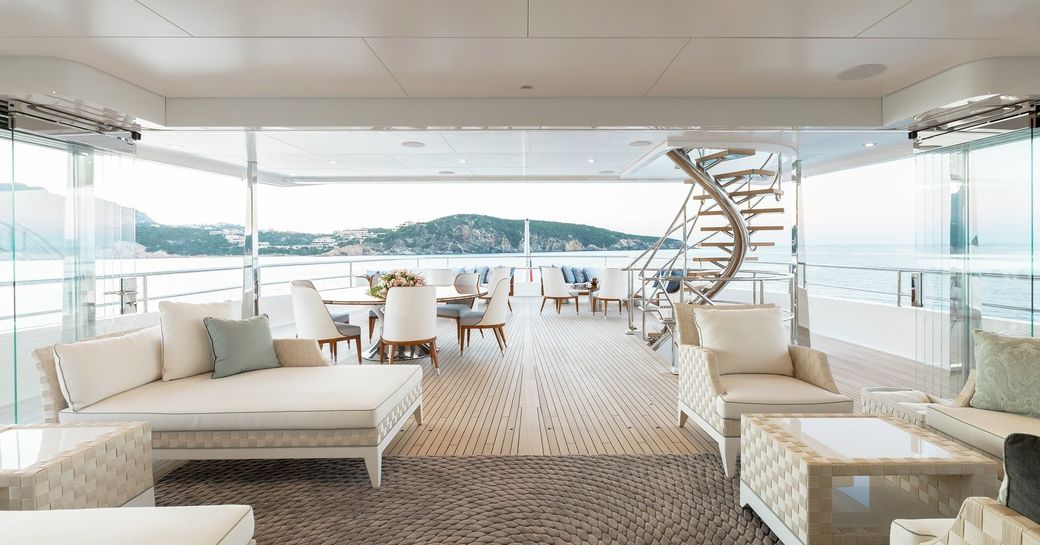 exterior main deck of feadship motor yacht joy, with seating and steps leading to deck above