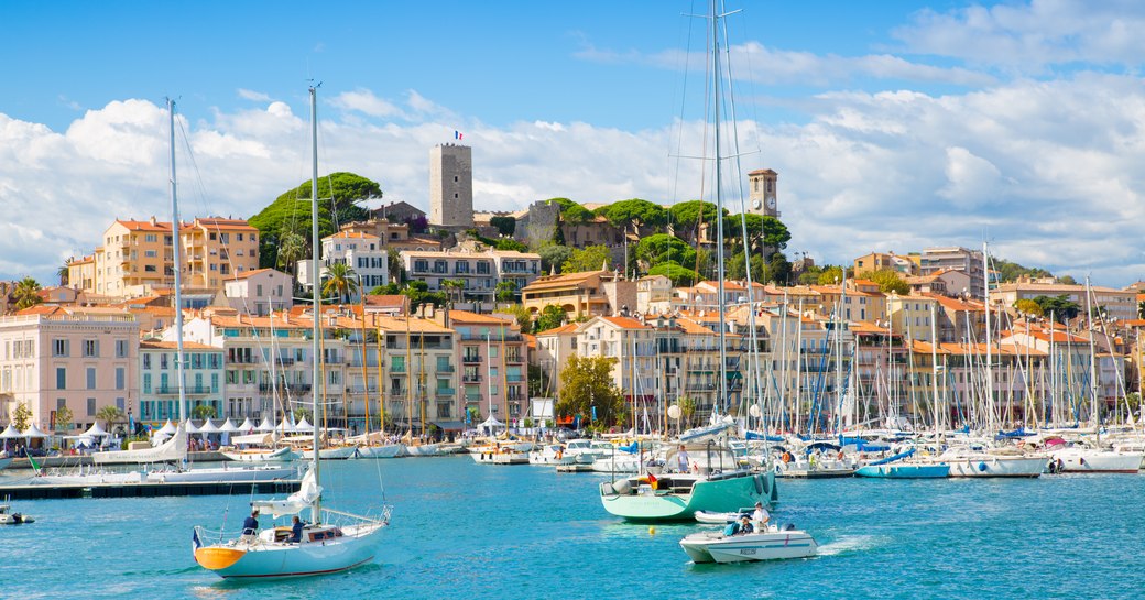 Overview of Cannes marina. Viewed from a vessel at sea, many motor yachts and sailing boats berthed, overlooking Cannes.