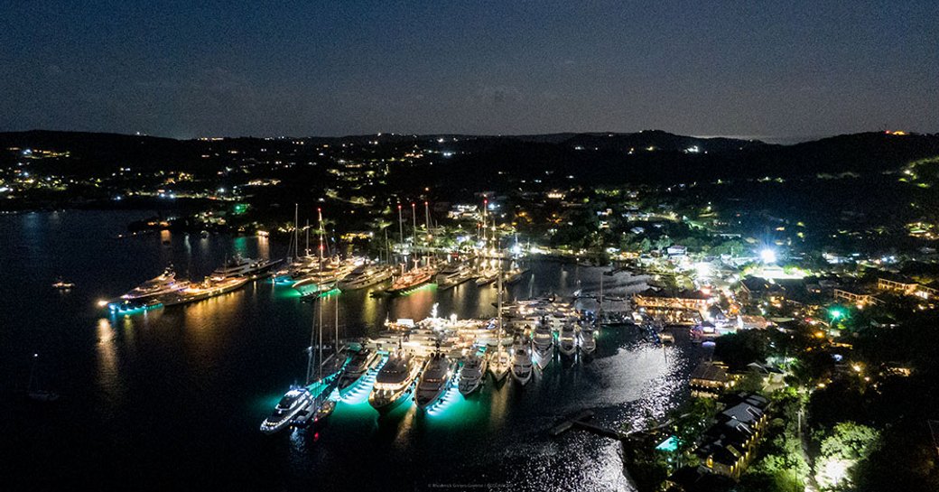 Overview of Nelson's Dockyard at night. Many motor yachts berthed with all the lights on.