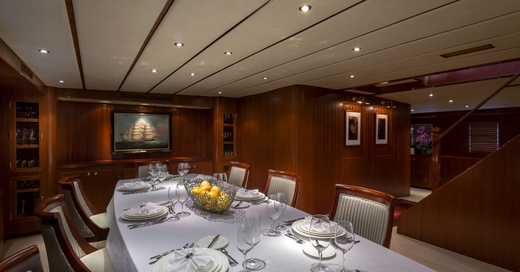 indoor dining table on charter yacht northern sun with polished wood and picture hanging on wall