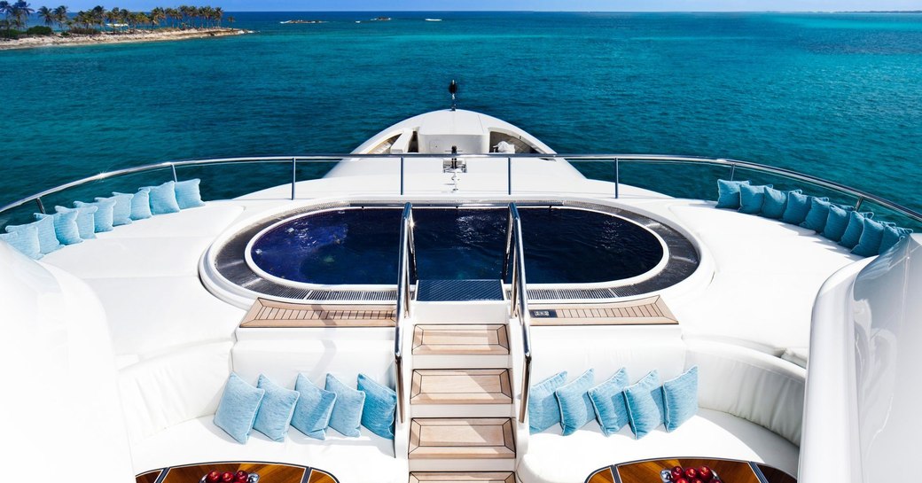 Pool on deck of charter yacht Lady E, with steps leading up to it and vast expanse of clear sea behind