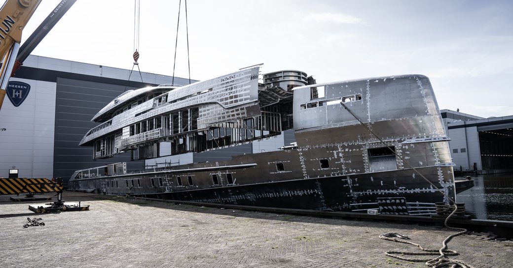 Side view of Heesen superyacht Project Orion having her hull and superstructure joined outside the construction shed.