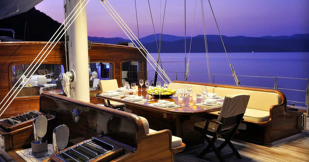 al fresco dining area on the foredeck of superyacht Aria I as the sun is setting