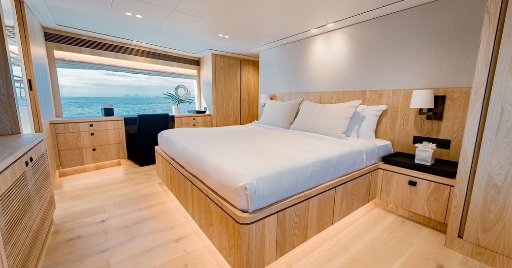 Master cabin onboard luxury yacht rental SEA-RENITY, central berth facing forward with wide window in the background