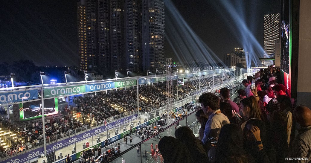 Overview of crowds in the stands watching over the Jeddah Corniche Circuit at night.