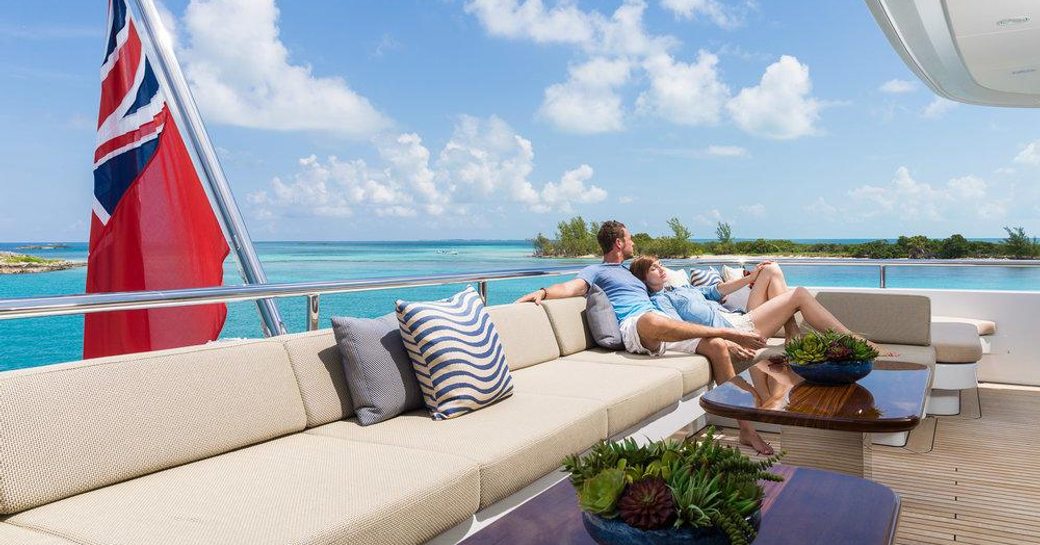 Charter guests relax on the aft deck of superyacht ELYSIAN