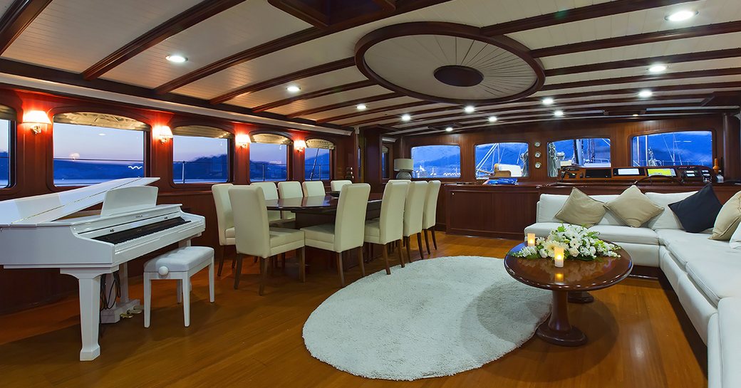 mahogany-clad main salon with white sofa, dining table and piano on board superyacht Aria I 